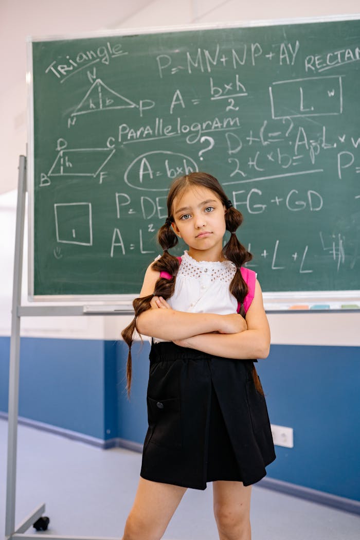 A confident young student stands with arms crossed in front of a blackboard displaying geometric equations.